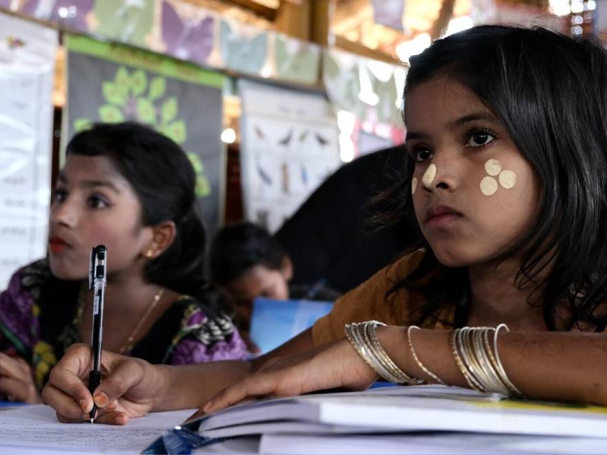 Dos jovenes rohingya toman apuntes para no perder detalle en clase