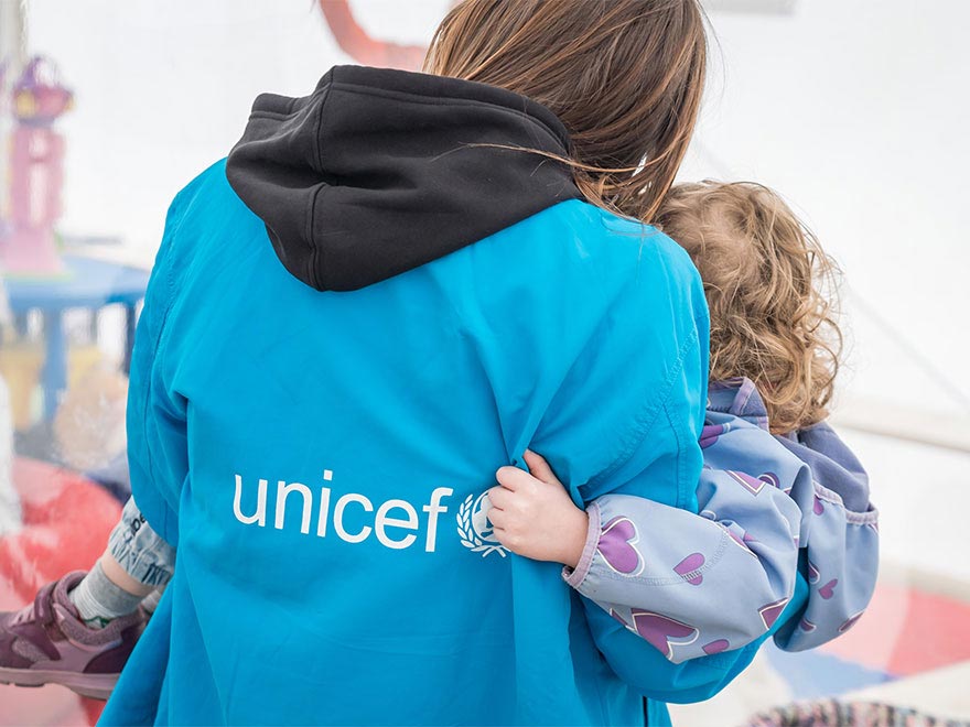 Imagen de un trabajador de UNICEF abrazando a una niña