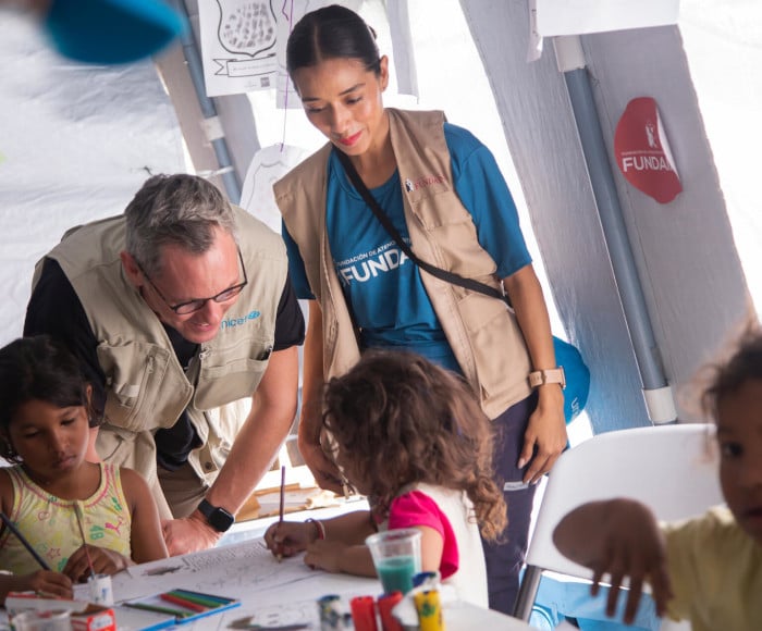 Personal de UNICEF junto a los niños en un espacio temporal habilitado por UNICEF