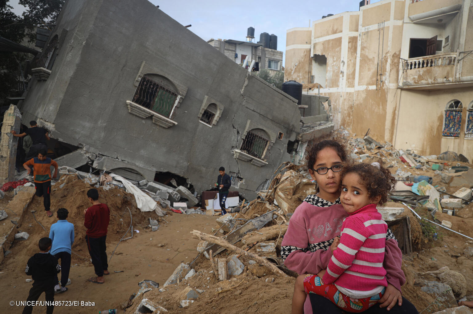 Abeer, de 12 años, sostiene en brazos a su hermana Zahra, de 4, frente a su casa destruida en Rafah, al sur de la Franja de Gaza.