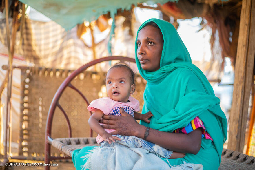 Malaz lleva en brazos a su hija Aida, de dos años, en su casa del estado de Kassala.