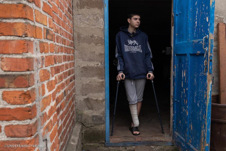 Yaroslav, de 16 años, que perdió la pierna derecha por la explosión de una mina hace seis meses y ya no puede andar. El chico está de pie con sus muletas junto a su casa. (Ucrania)