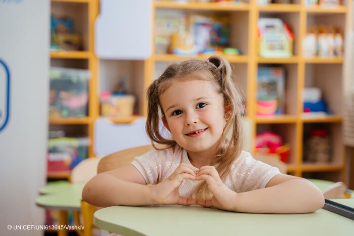 Una niña en edad preescolar está sentada en el pupitre de un aula de un centro de apoyo a la educación infantil en Ucrania