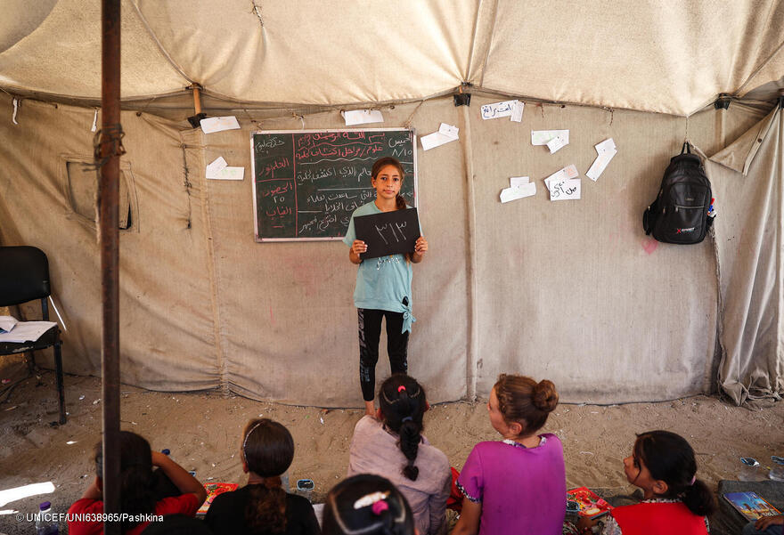 El 15 de agosto de 2024, en el Campamento Deir Al-Balah en la Franja de Gaza, Estado de Palestina, Hala, de 11 años, sostiene una pizarra que muestra el número de días escolares que ha perdido: 313