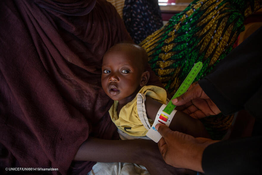 Personal sanitario mide la circunferencia del brazo de un niño para comprobar si sufre desnutrición