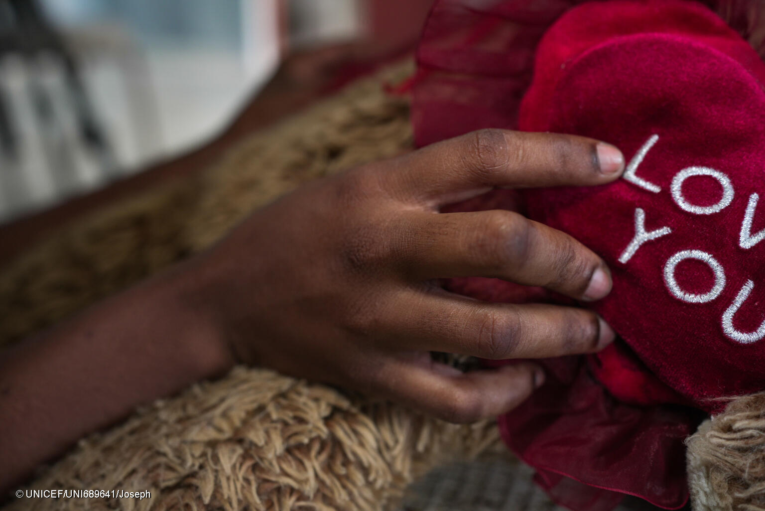 manos de un niño sobre un peluche rojo con el texto 'love you'