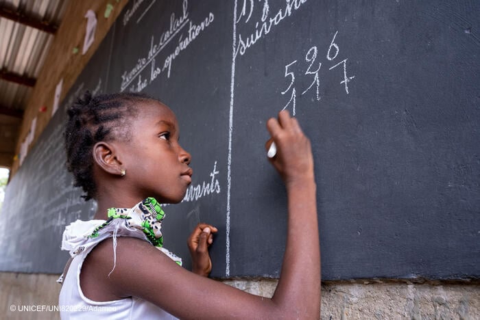 Una niña escribe en una pizarra en un espacio de aprendizaje temporal en Burkina Faso.