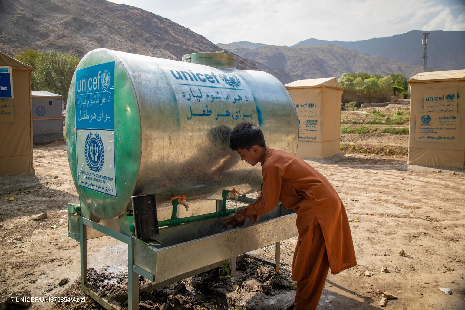 niño afgano bebiendo de uno de los suministros de agua instalados por UNICEF en un campo de refugiados