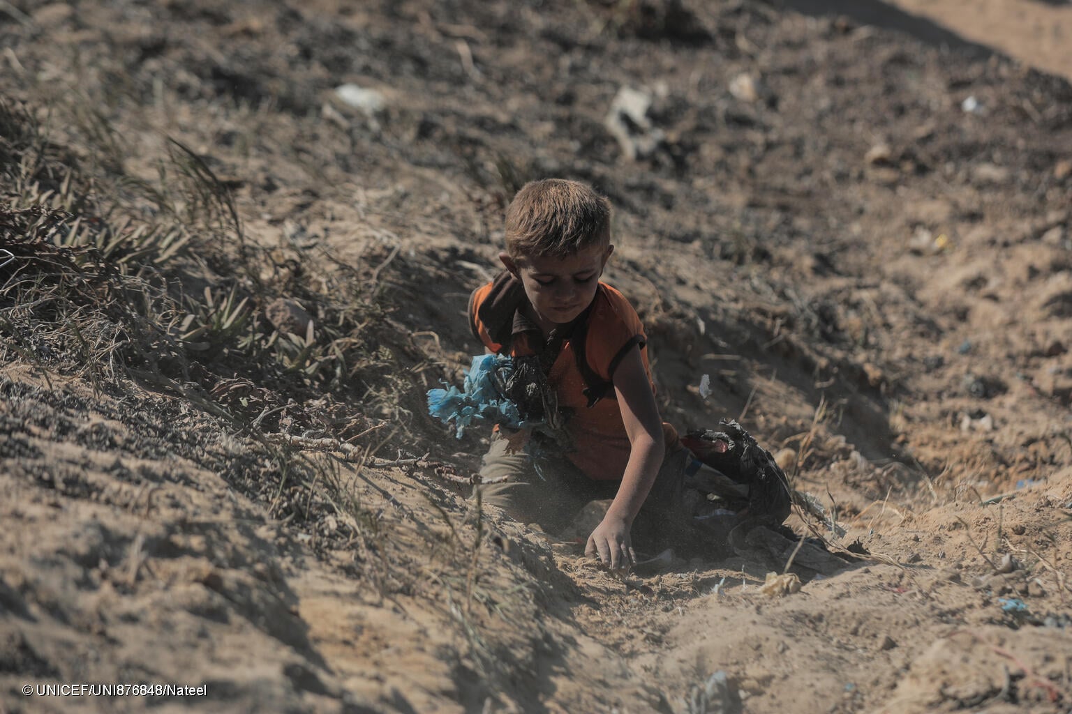 niño en Gaza buscando entre escombros y tierra