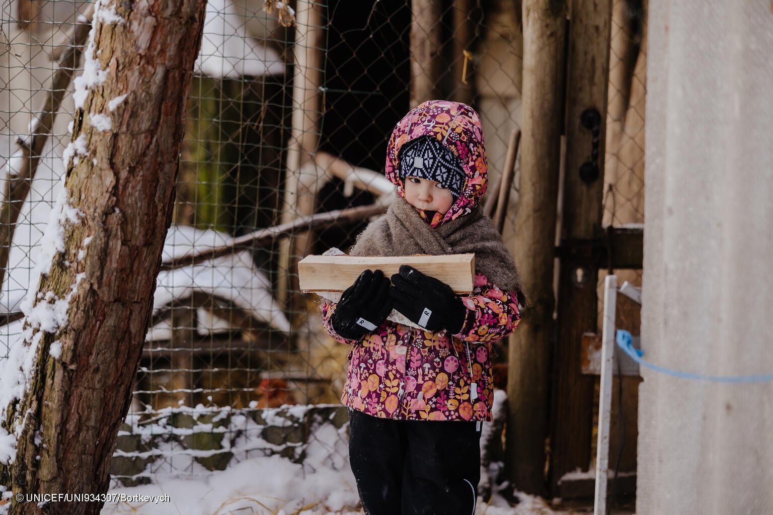 niña carga con trozos de madera en el frío invierno en Ucrania
