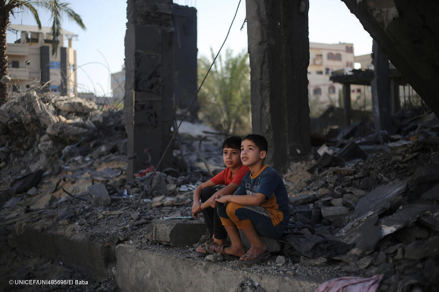 Dos niños sentados entre los escombros de los edificios atacados