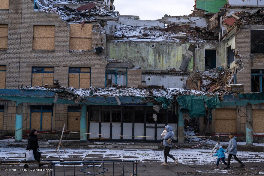 Una familia ucraniana pasa por delante de un edificio destruido por la guerra