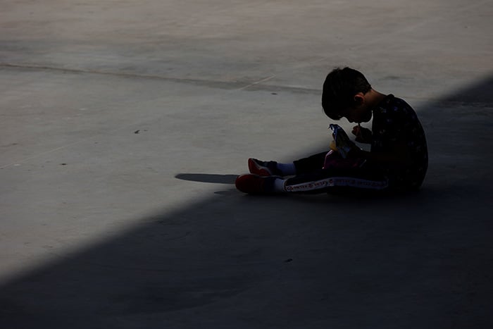 Un niño almuerza en el patio de su colegio a la sombra durante el recreo