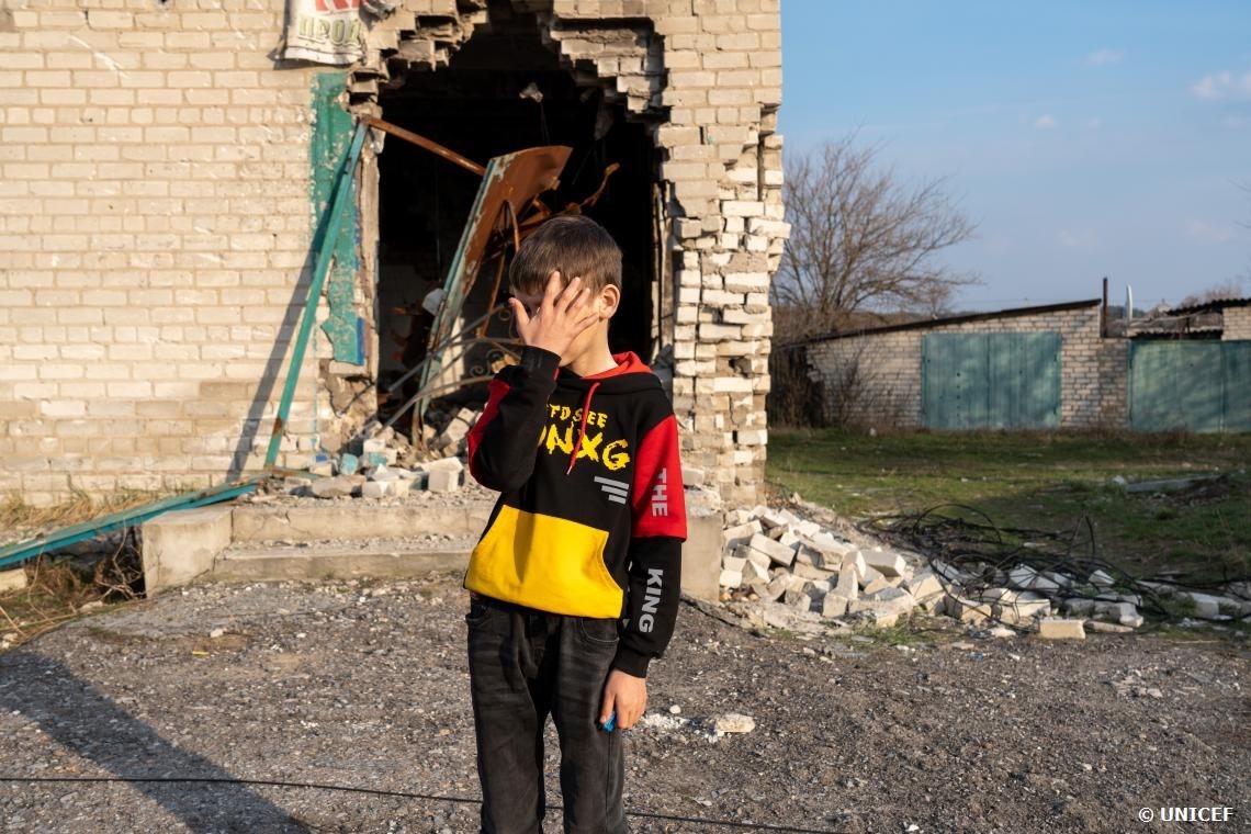 Un niño frente a las ruinas de un edificio destrozado por el conflicto