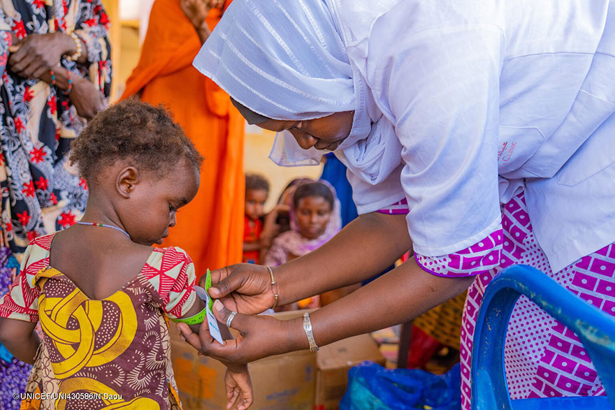 Personal sanitario mide la circunferencia del brazo de un bebé en Malí