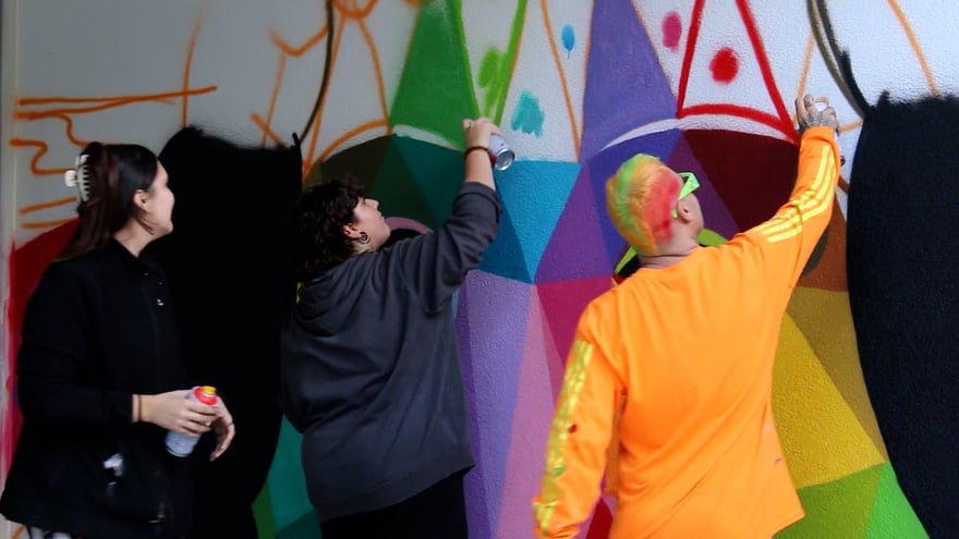 Okuda y adolescentes trabajando en el mural