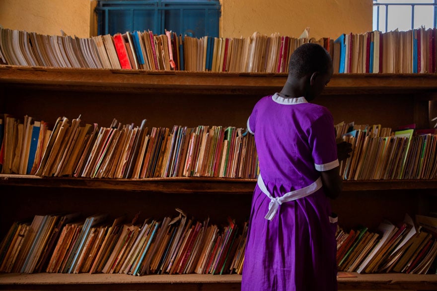 Una niña busca un libro que leer en la biblioteca de su escuela en Uganda