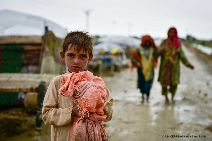 Un niño se aferra a sus pertenencias mientras las familias se mudan a áreas más seguras tras las inundaciones.