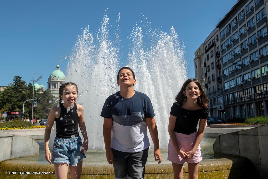 Tres niños combaten el calor en una fuente en una ciudad europea