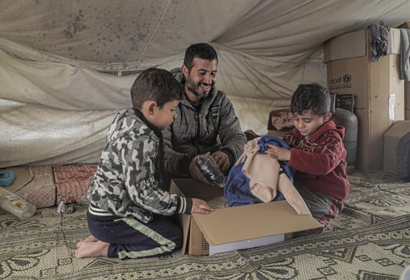 niños abren un paquete con ropa de abrigo para protegerles del frío del invierno