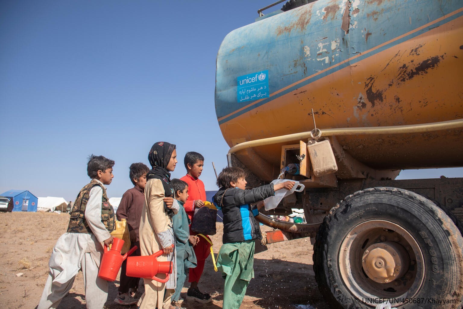 Niños afganos esperan para recoger agua de uno de los camiones cisterna de UNICEF
