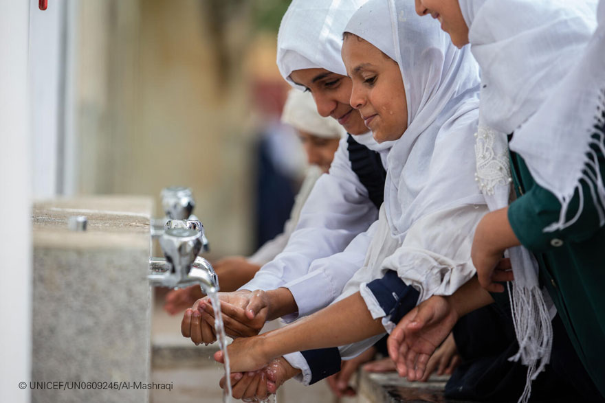 Una niña se lava las manos y la cara en las instalaciones de una escuela de Yemen