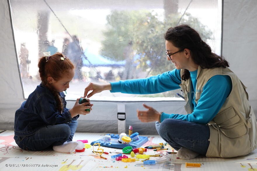 Personal de UNICEF juega con una de las niñas afectadas por el conflicto en uno de los espacios acogedores de UNICEF