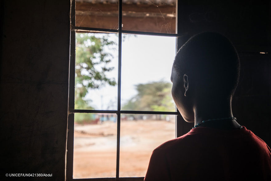 Una adolescente mira a través de una ventana en Uganda