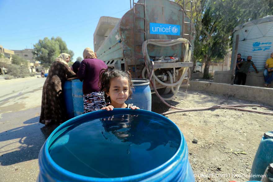 Una niña siria junto a uno de los camiones de UNICEF que transportan agua dentro del país.