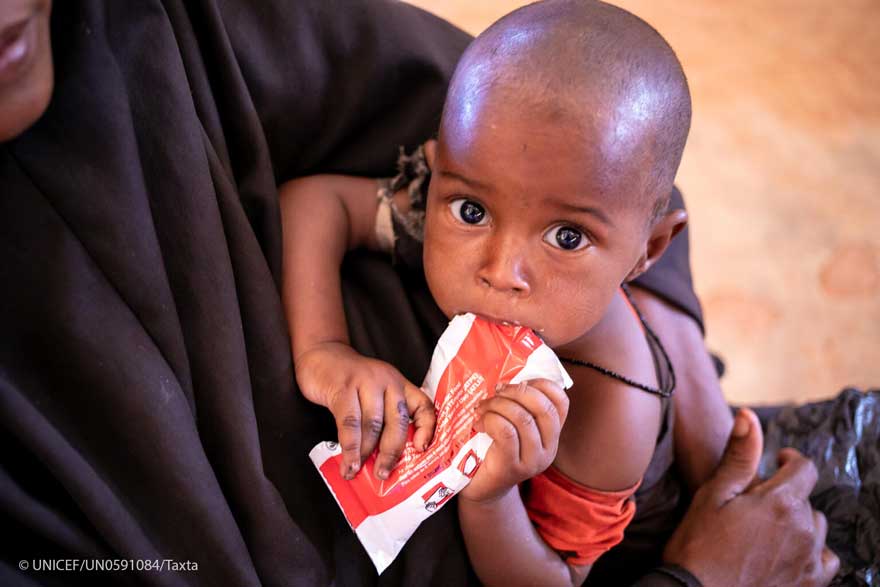 Un niño toma un sobre de alimento terapéutico en un centro de salud de Somalia