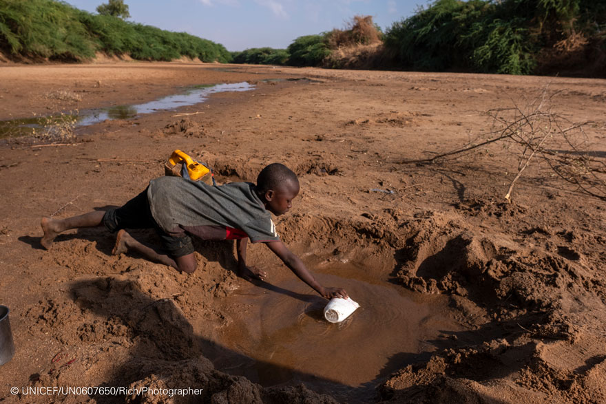 Un niño recoge agua en un río casi seco debido a la sequía en Somalia