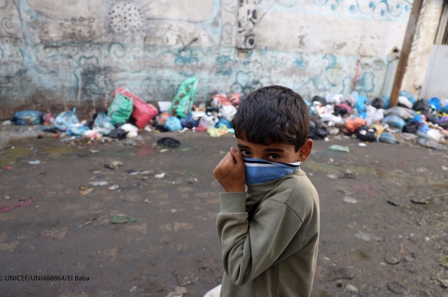 Un niño se tapa la boca para protegerse del polvo de los escombros en la Franja de Gaza