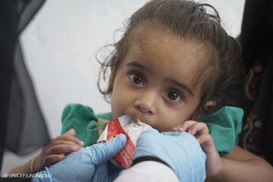 Una niña tomando alimentación terapéutica en una clínica de Yemen