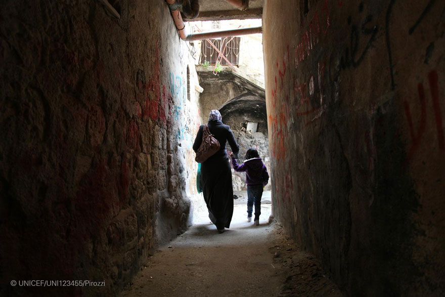 Una mujer palestina y su hija caminan por un callejón