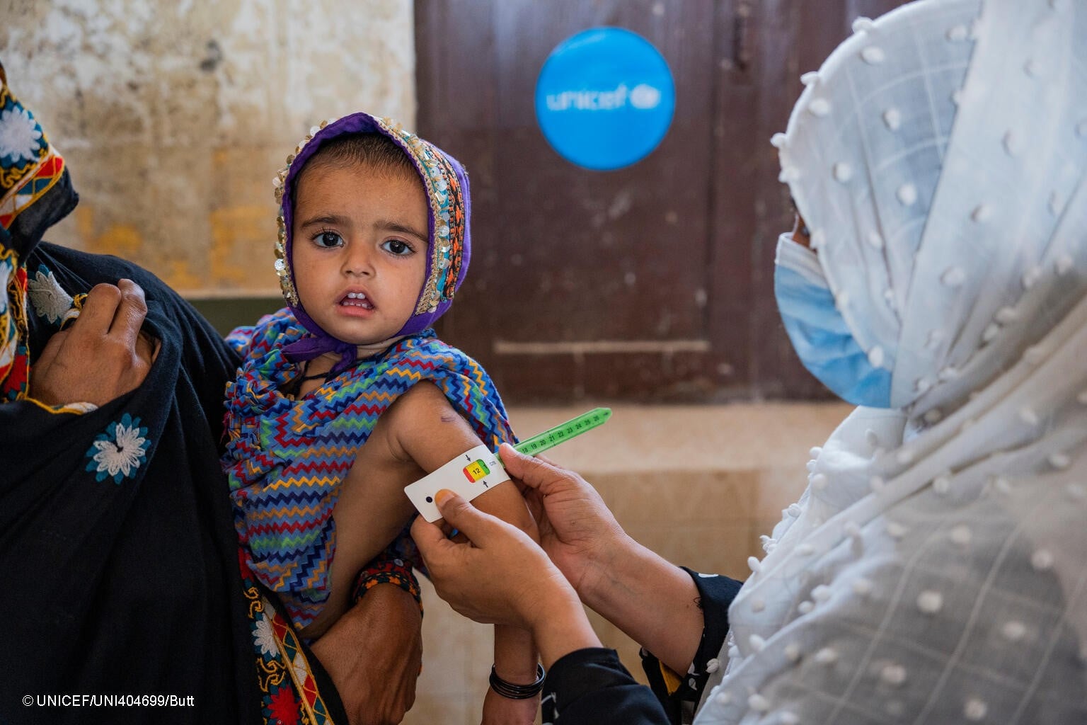 Personal sanitario mide la circunferencia del brazo de un bebé en Pakistán