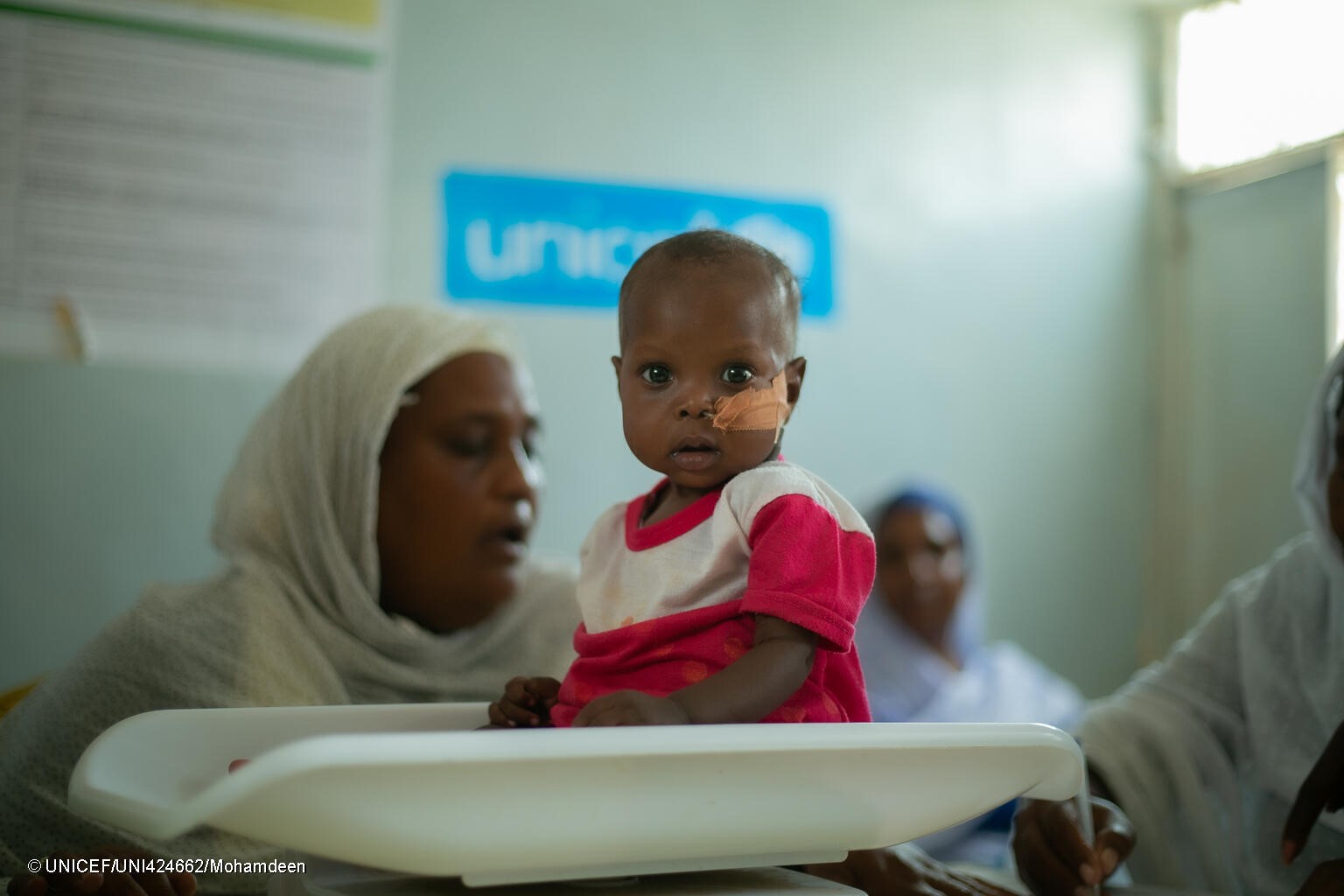 Un bebé sudanés sentado sobre una báscula en una de las clínicas que UNICEF apoya en el país