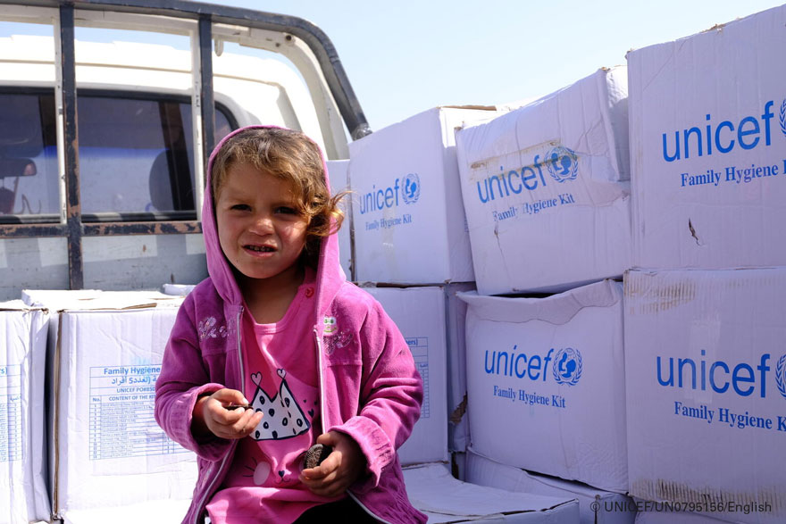 Una niña siria junto a los suministros de UNICEF distribuidos en su campamento de desplazados