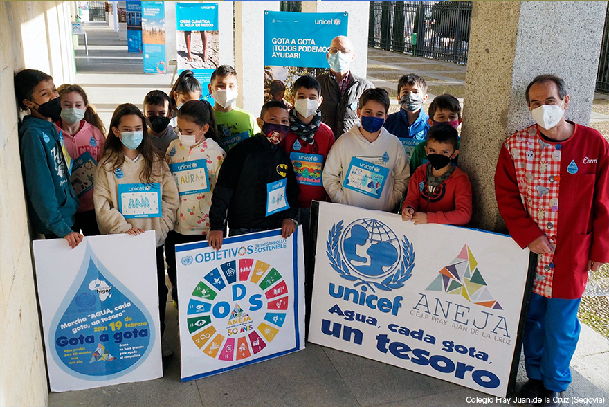 Un grupo de estudiantes y su profesor posan junto a la exposición del agua de UNICEF portando unos carteles sobre la carrera de gotas