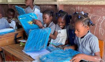 Unas niñas de Haití abren ilusionadas sus libros escolares de UNICEF en la escuela