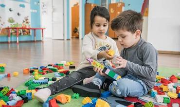 Ilinca, niña rumana de 5 años, ayuda a Karim, niño ucraniano de 3 años, a construir una torre con ladrillos LEGO en el centro Play, learning and parenting de Bucarest el 10 de octubre de 2022.