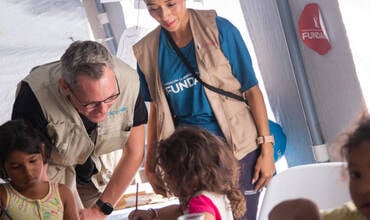 Personal de UNICEF junto a los niños en un espacio temporal habilitado por UNICEF