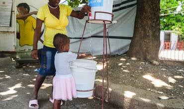 Tras recuperarse do cólera, esta nena lávase as mans antes de saír do centro de saúde Saint Michel de l'Attalaye, no departamento de Artibonite.