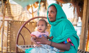 Malaz lleva en brazos a su hija Aida, de dos años, en su casa del estado de Kassala.
