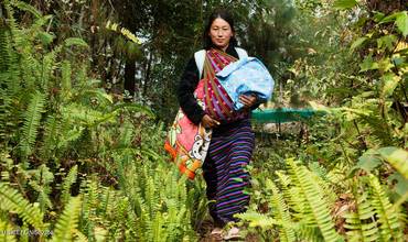 Sangay, de 29 años, camina por el bosque hasta la clínica para vacunar a su hijo recién nacido. Tiene que caminar durante una hora para llegar a la clínica.