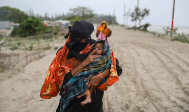 Habitantes de la aldea de Panjupara caminan hacia el refugio con sus hijos y valiosos enseres domésticos durante las lluvias en Kuakata, en previsión de que el ciclón Remal toque tierra en Bangladesh el 26 de mayo de 2024.