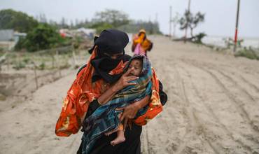 Habitantes de la aldea de Panjupara caminan hacia el refugio con sus hijos y valiosos enseres domésticos durante las lluvias en Kuakata, en previsión de que el ciclón Remal toque tierra en Bangladesh el 26 de mayo de 2024.