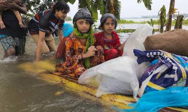 Niños atraviesan las aguas de la inundación en una balsa improvisada, en busca de refugio, en Feni.