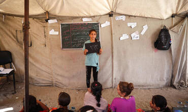 El 15 de agosto de 2024, en el Campamento Deir Al-Balah en la Franja de Gaza, Estado de Palestina, Hala, de 11 años, sostiene una pizarra que muestra el número de días escolares que ha perdido: 313