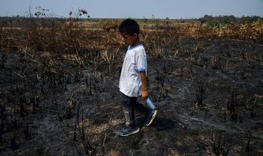 Un niño camina por un área devastada por el fuego en Perú