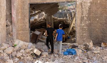 Niños y niñas frente a los escombros de un ataque en la Franja de Gaza